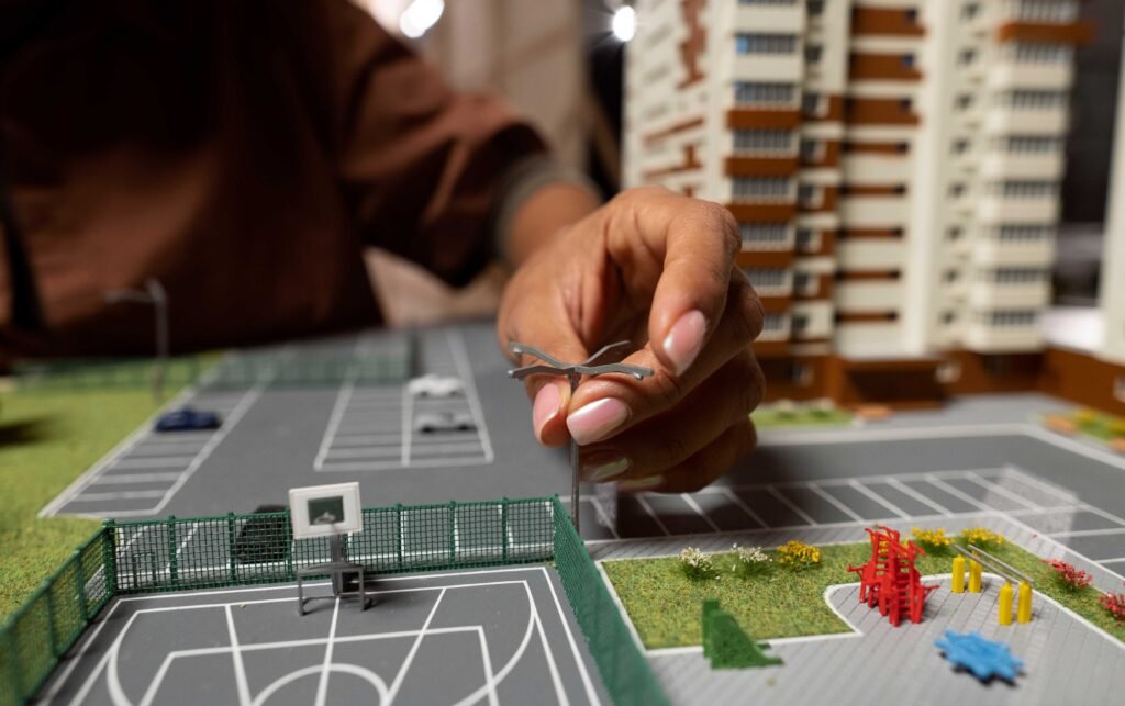 Hand placing model tree in real estate site plan with buildings and parking layout.